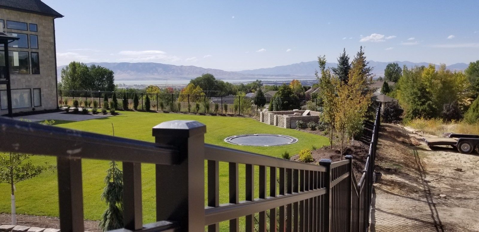 A large house is behind a fence with a view of a lush green field.