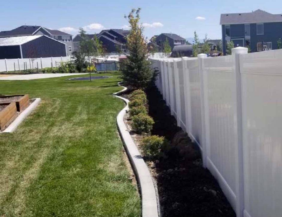 A white fence surrounds a lush green yard.