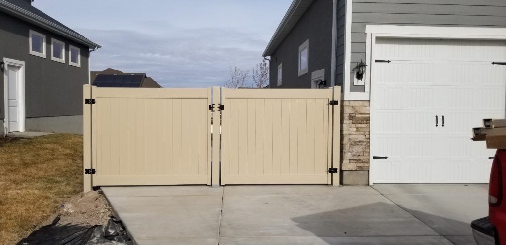 A wooden gate is sitting in front of a garage next to a house.