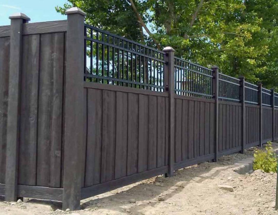 A wooden fence with a metal railing is surrounded by trees.