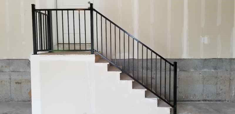 A set of stairs with a black railing in a garage.