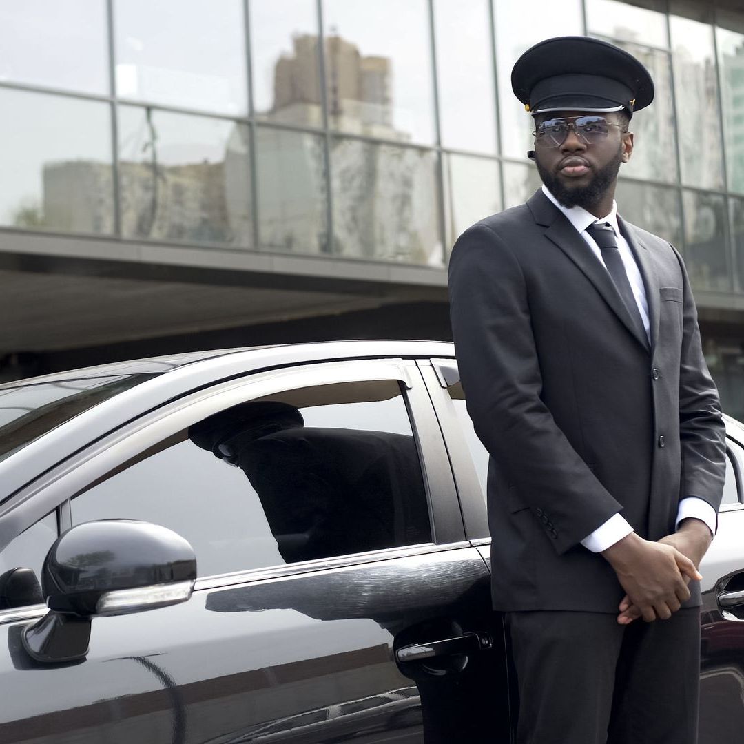 A man in a suit and hat is standing next to a car