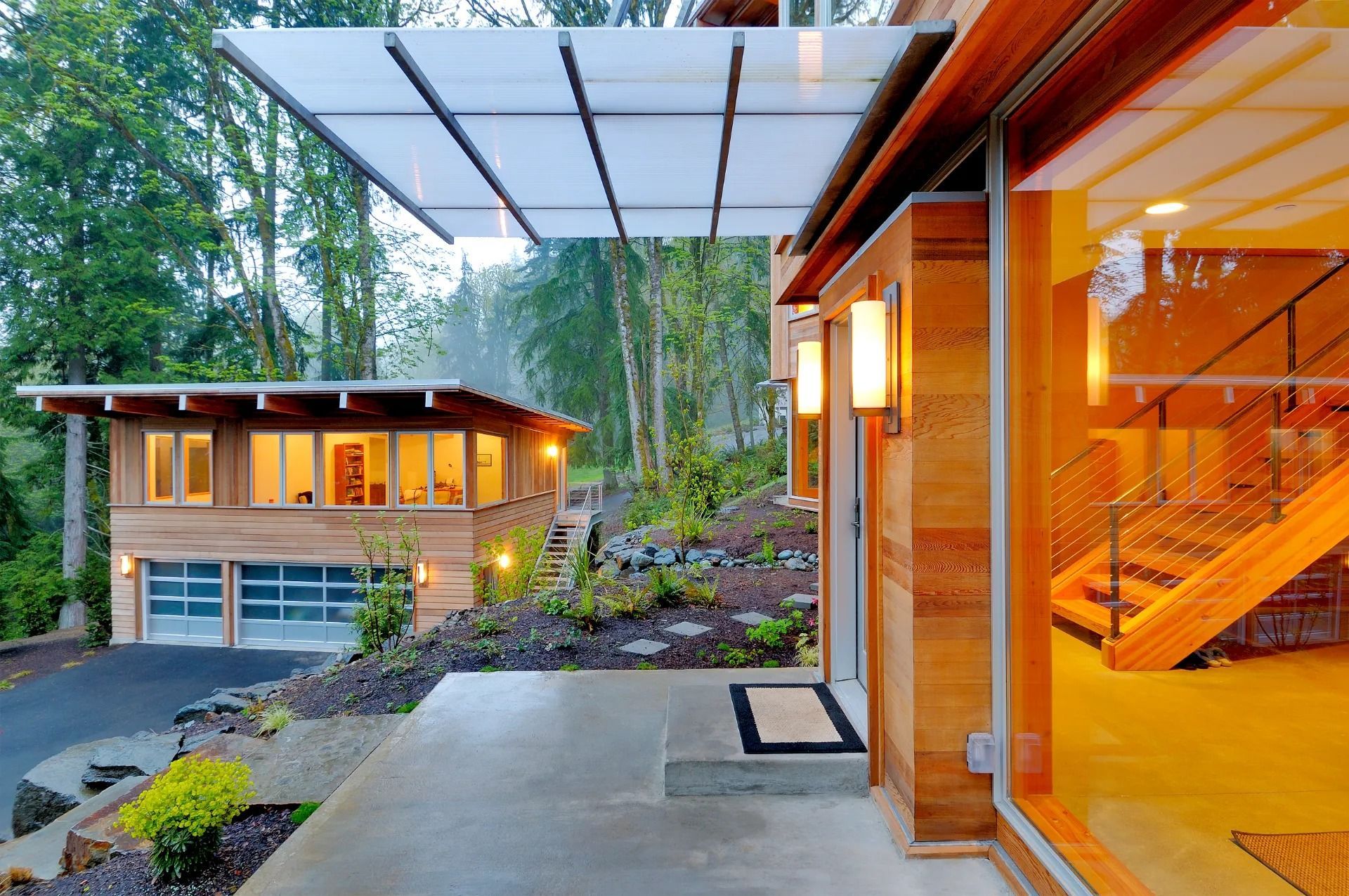 Modern home exterior with a covered entryway and a garage, surrounded by trees.