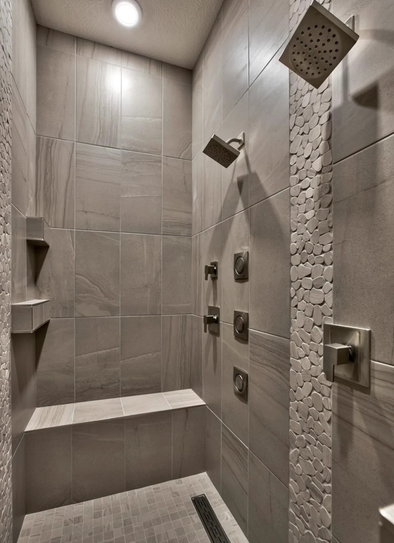 Modern shower with stone tile, multiple shower heads, and built-in bench.