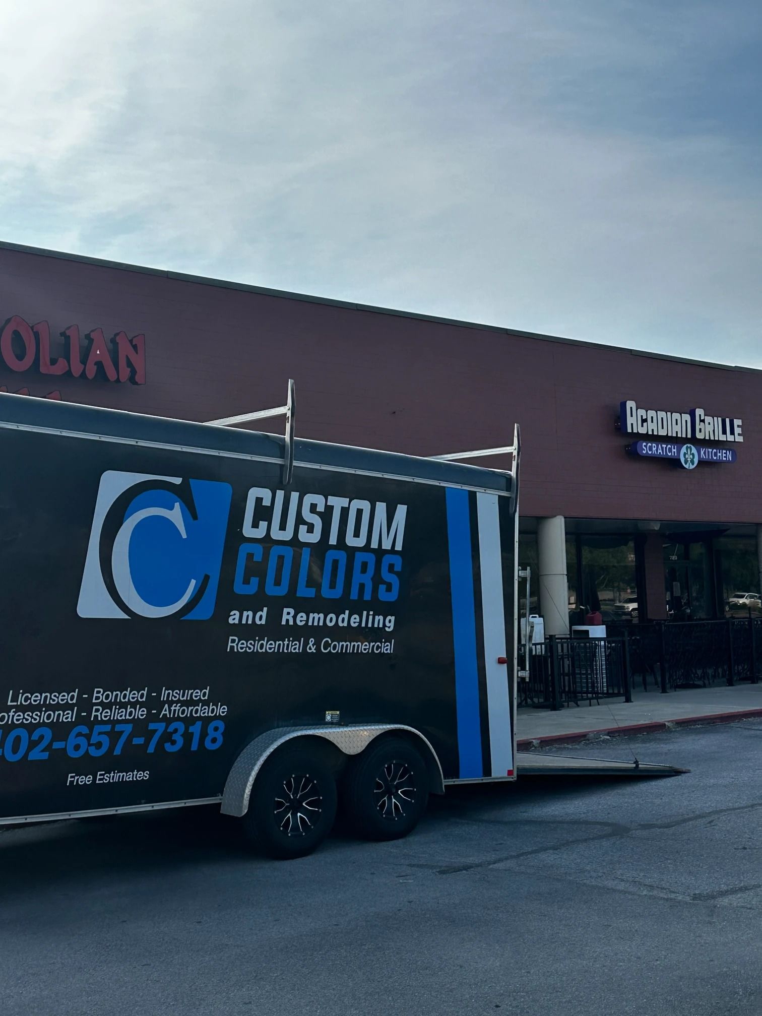A trailer for Custom Colors and Remodeling parked outside a building with 