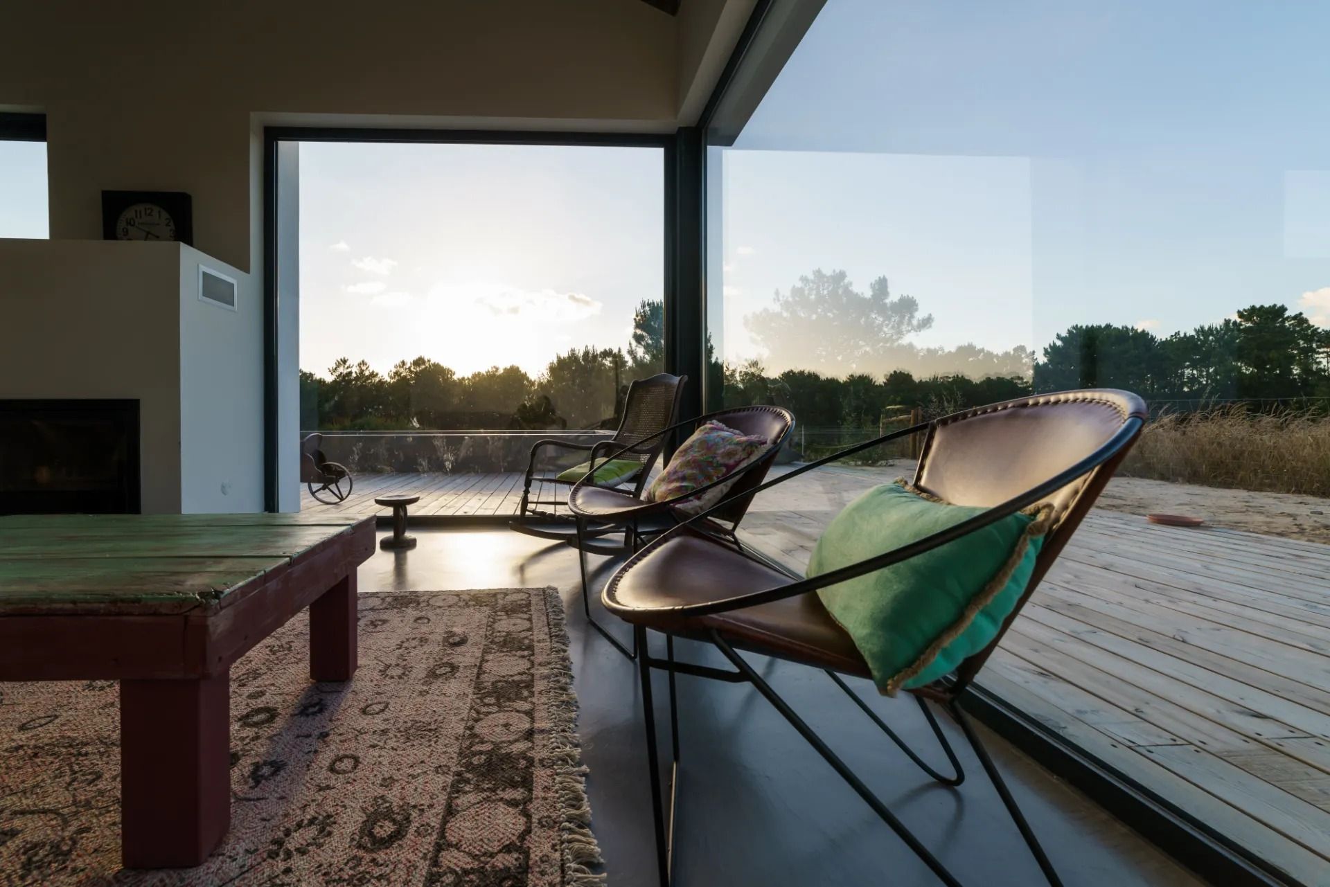 Modern living room with glass wall overlooking landscape. Chairs face the view.
