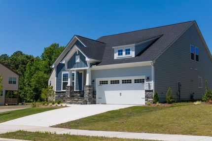 New gray suburban house with a white garage and driveway under a clear blue sky