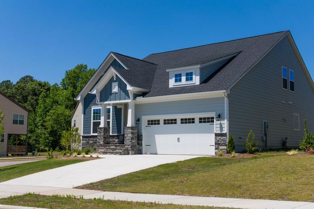 New gray suburban house with a white garage and driveway under a clear blue sky