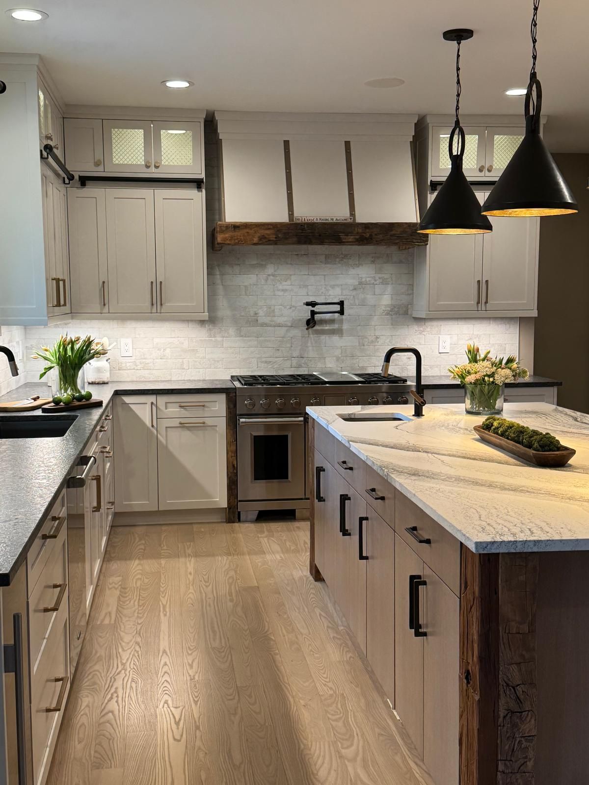 Modern farmhouse kitchen with white cabinets, wood island, black pendant lights, and marble countertops