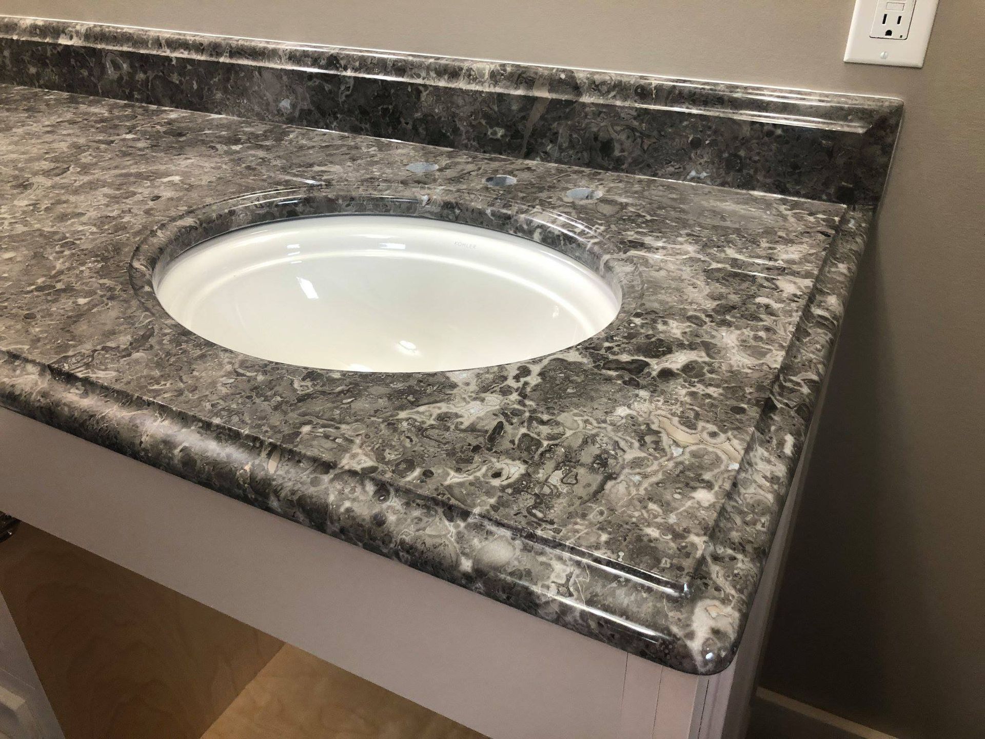 Granite bathroom vanity countertop with oval sink and white backsplash wall