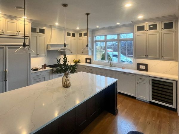 A kitchen with white cabinets and a large island in the middle.