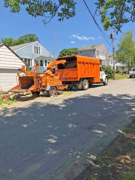 An orange wood chipper truck parked on a residential street during the day.