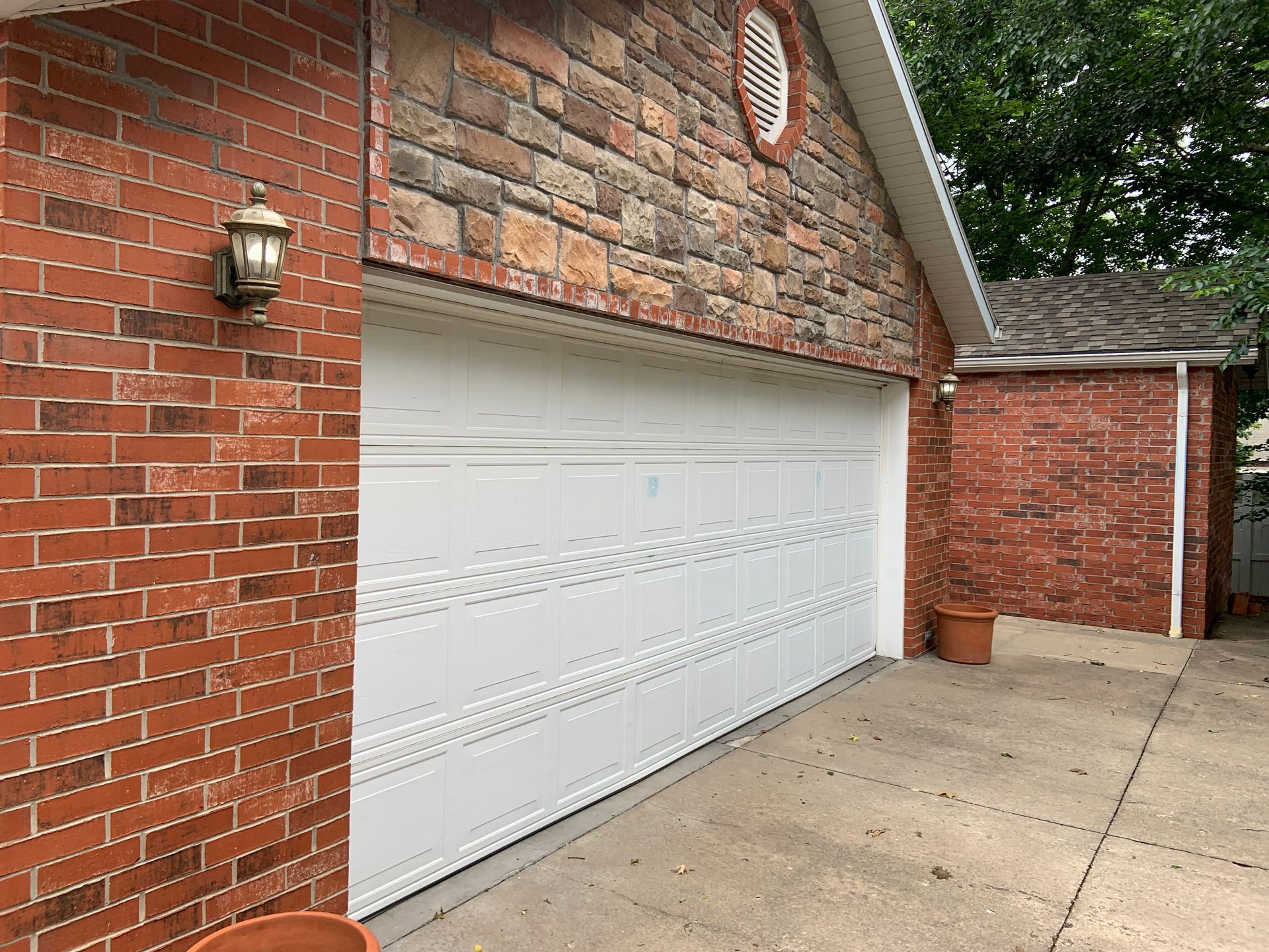 Red brick garage exterior with white garage door and adjacent brick wall.