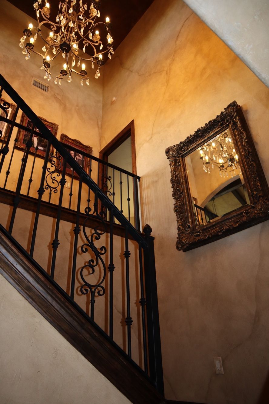 a staircase with a mirror and a chandelier hanging from the ceiling