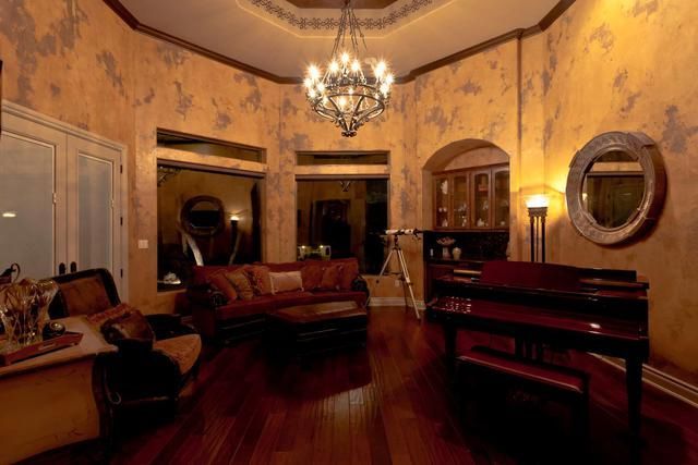 A living room with a piano, couch, chairs and a chandelier