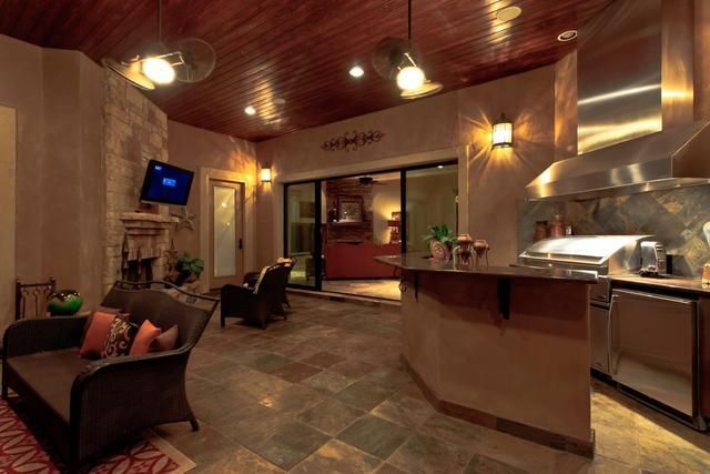 A living room with a couch and chairs and a kitchen with stainless steel appliances