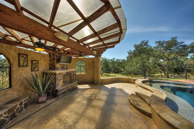 A patio with a fireplace and a swimming pool in the background