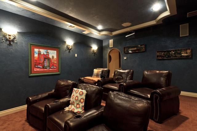 A home theater with brown leather chairs and a painting on the wall