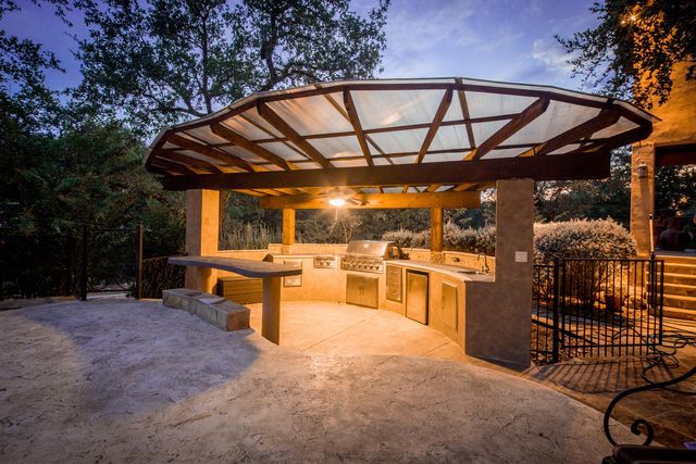 A large outdoor kitchen with a glass roof is lit up at night