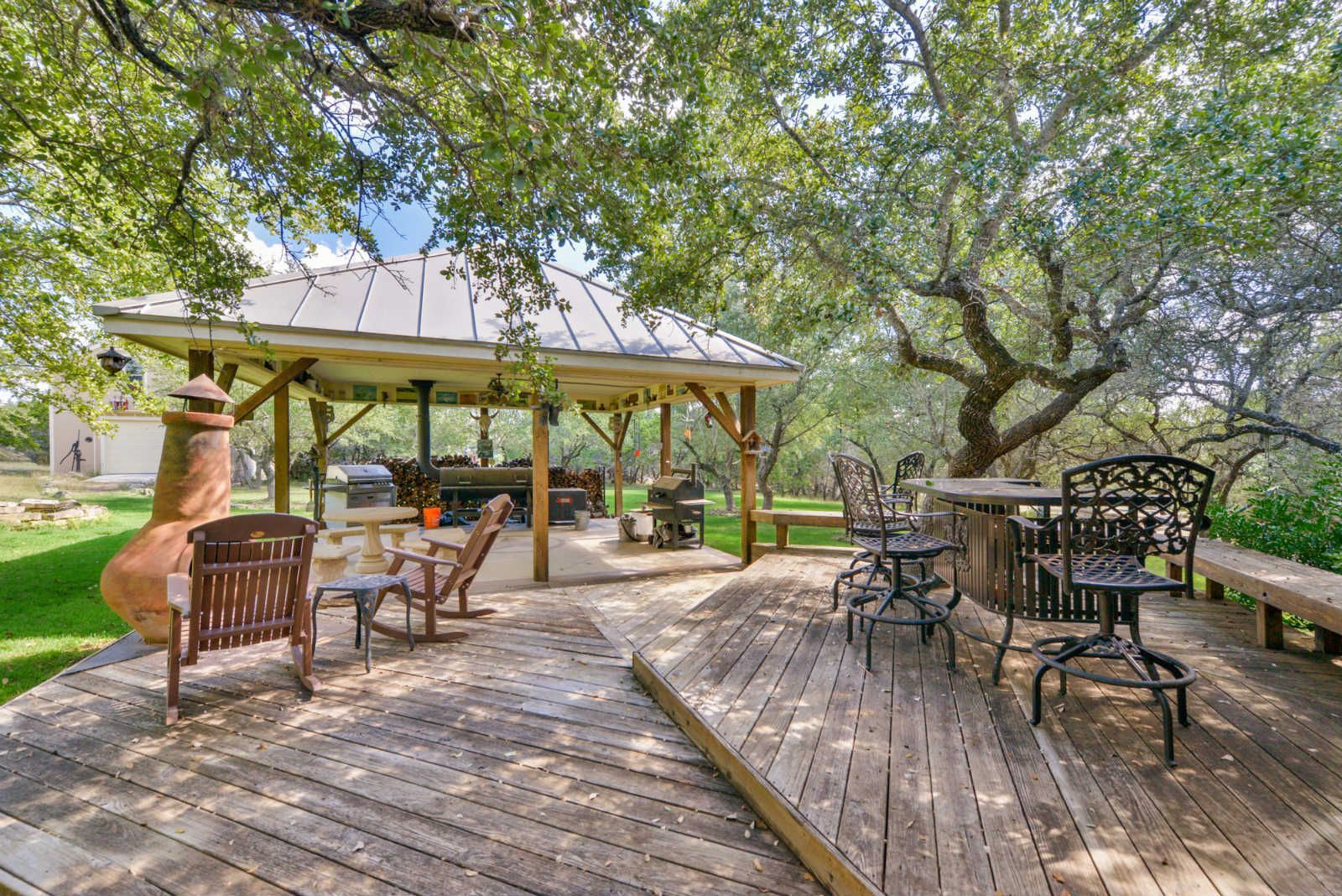 A wooden deck with tables and chairs under a gazebo