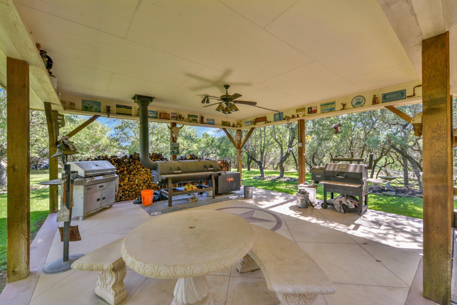 A covered patio with a table and benches and a grill .