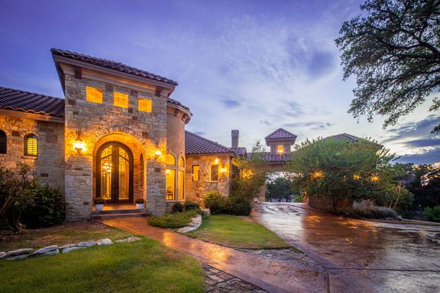 A large stone house with a tiled roof is lit up at night