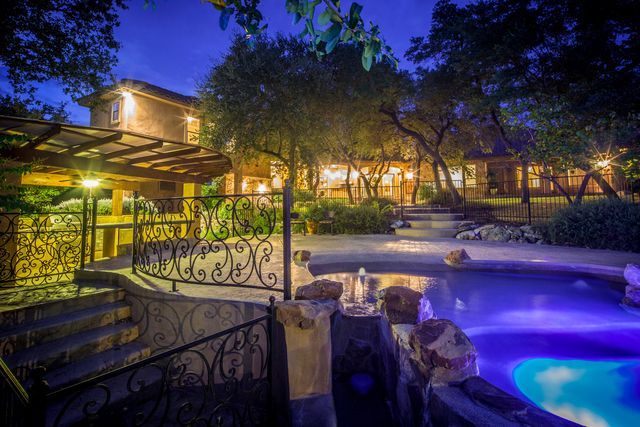 A large house with a swimming pool in front of it at night