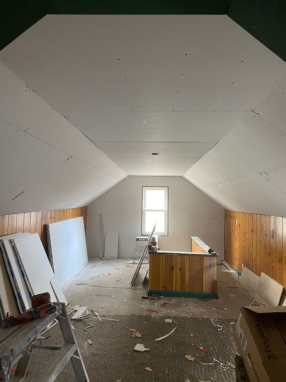 An empty attic with a ladder and a window