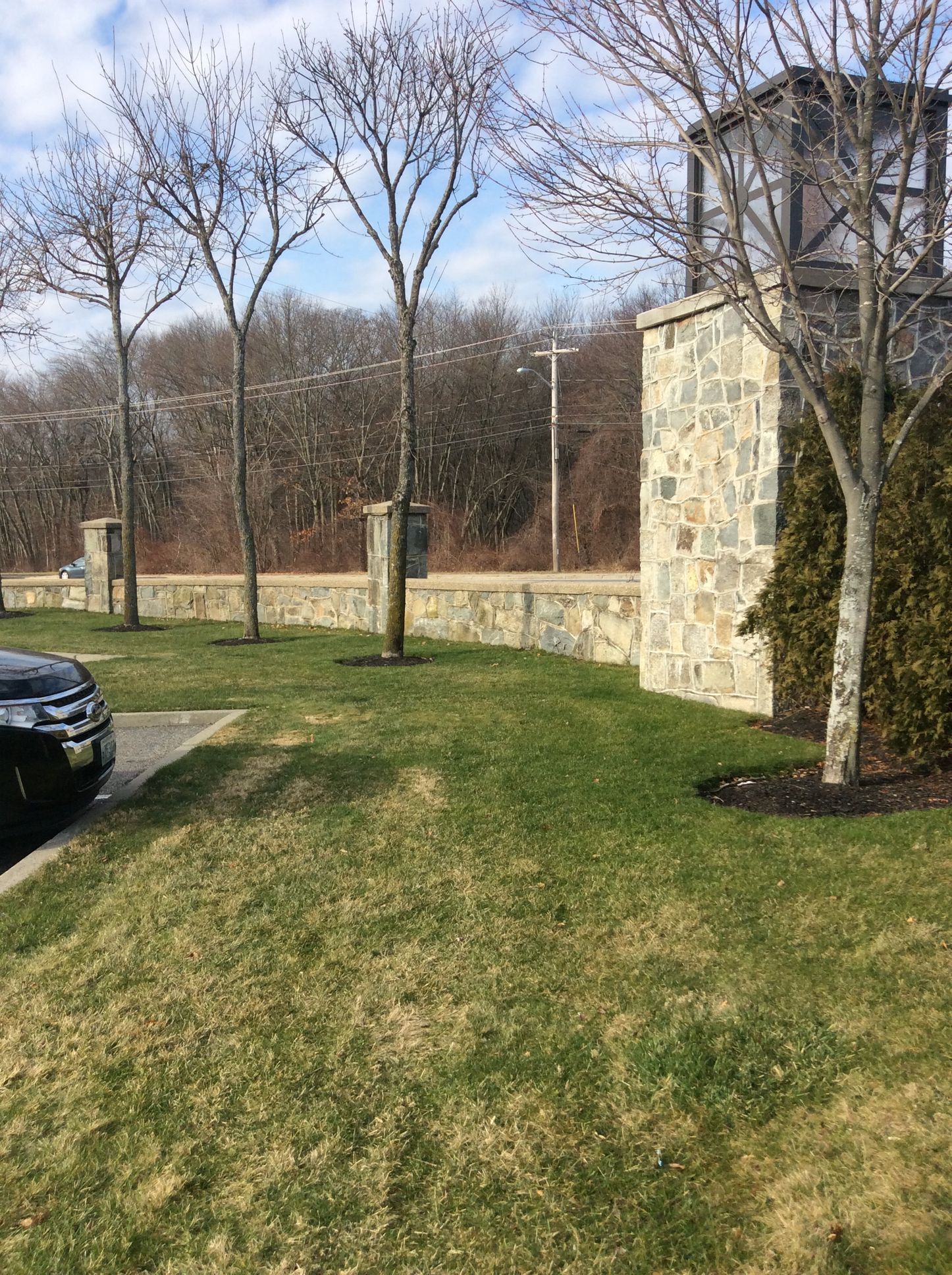 a black car is parked in front of a stone wall