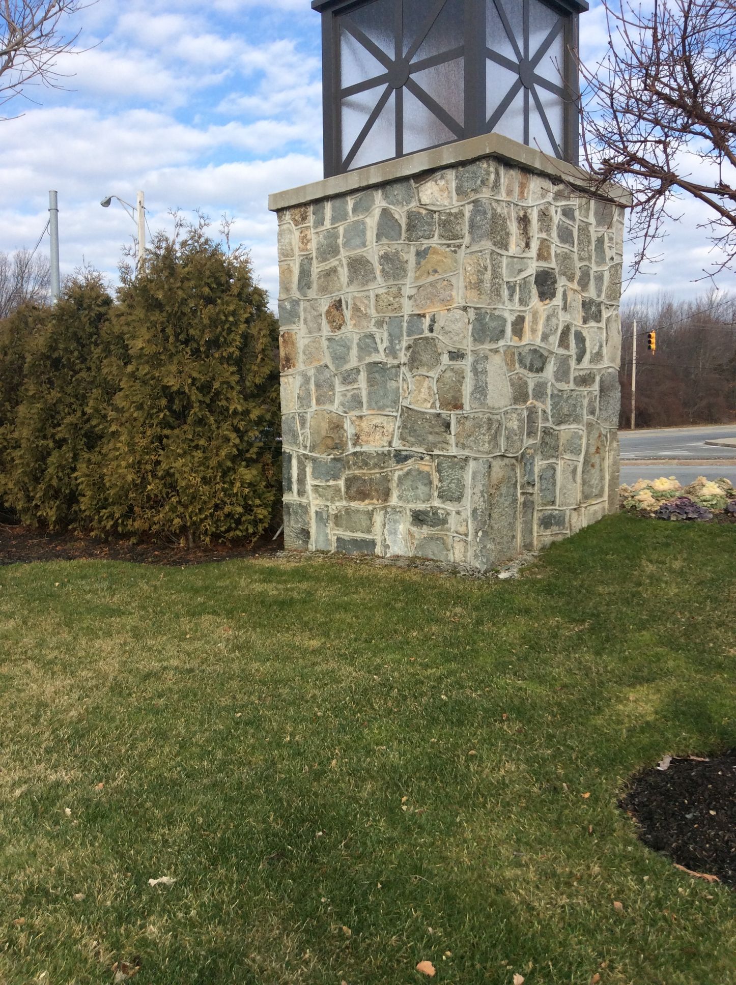 a stone pillar with a light on top of it in a grassy area