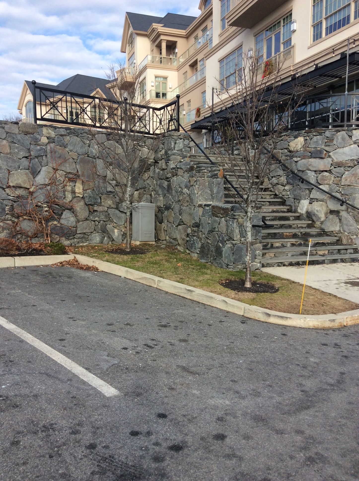 a parking lot with a stone wall and stairs in front of a building