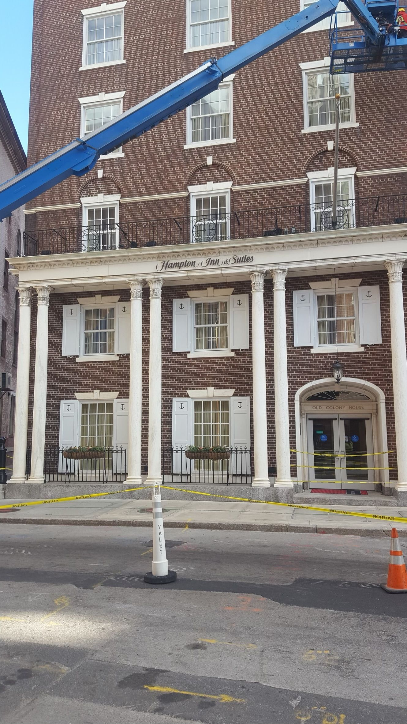 a large brick building with white shutters and a crane in front of it