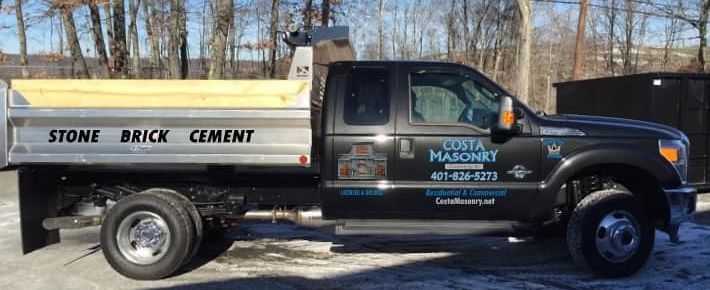 a dump truck is parked in a parking lot with trees in the background