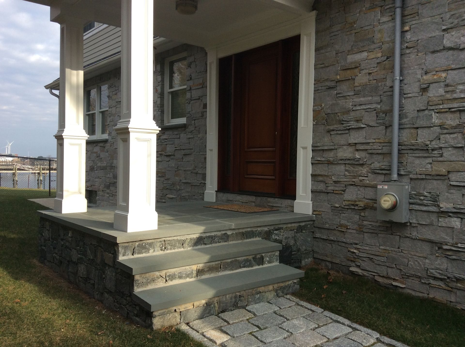 a stone house with a porch and steps leading to the front door