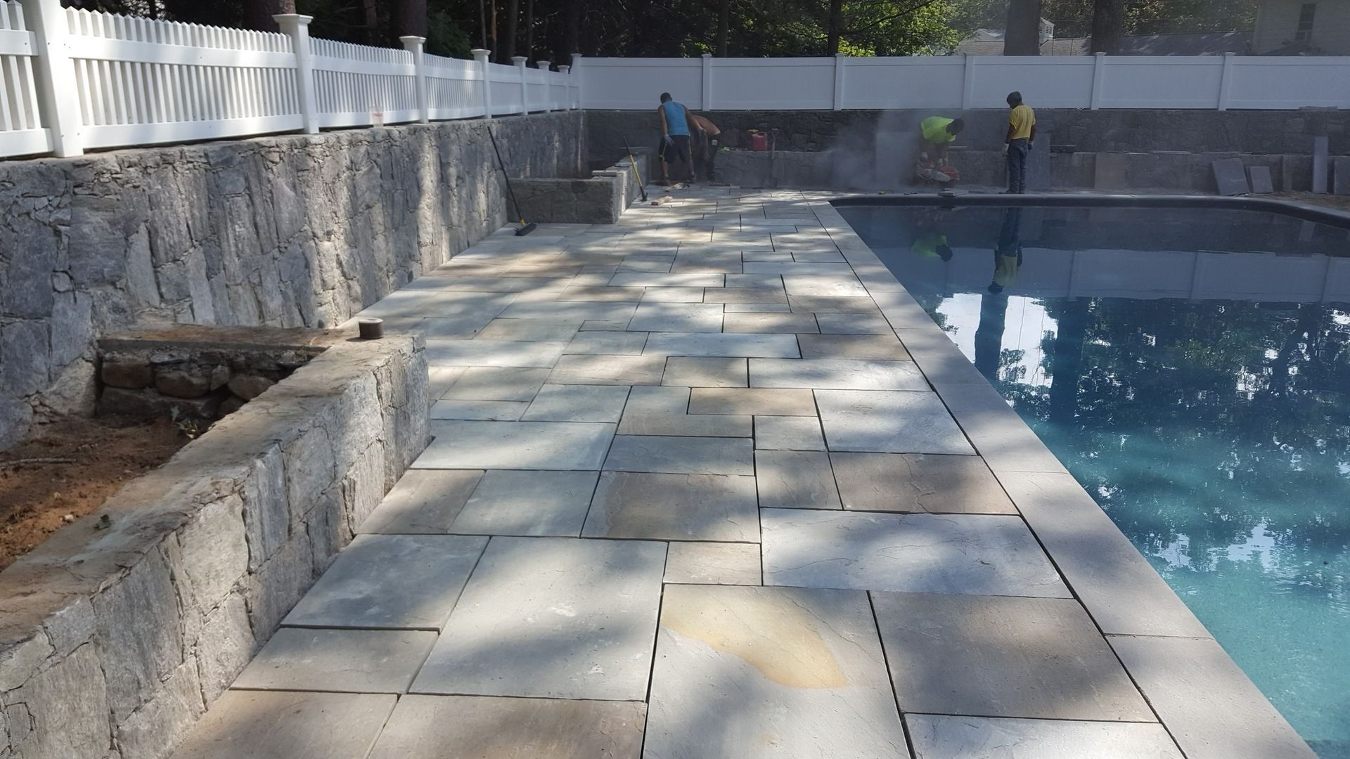 a white fence surrounds a large swimming pool