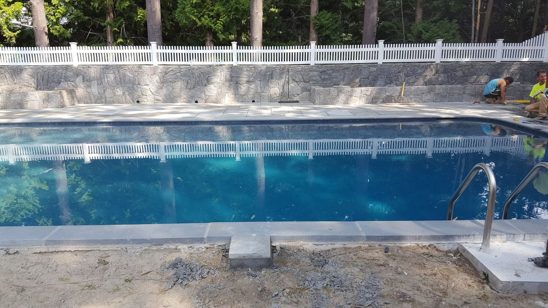 a large swimming pool with a white fence around it