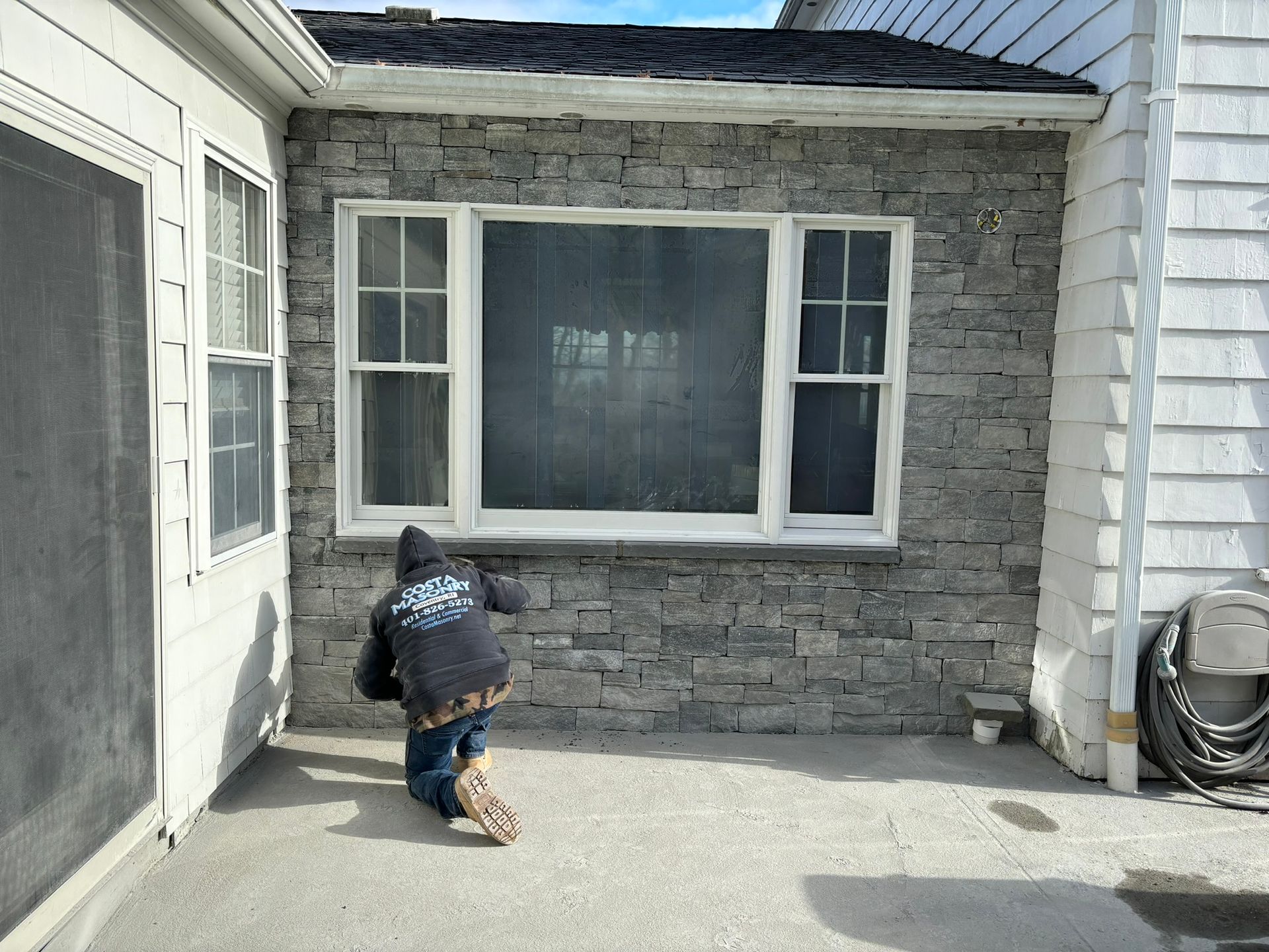 a man is standing in front of a brick wall with a window