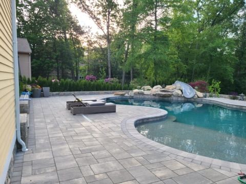 a large swimming pool with a patio in front of it