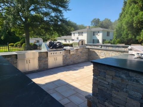 a patio with a grill and a house in the background