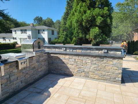 a patio with a stone wall and a pizza oven