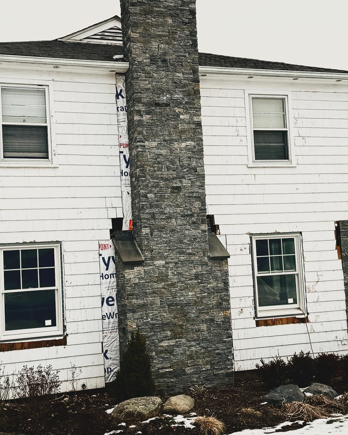 a white house with a stone chimney on the side