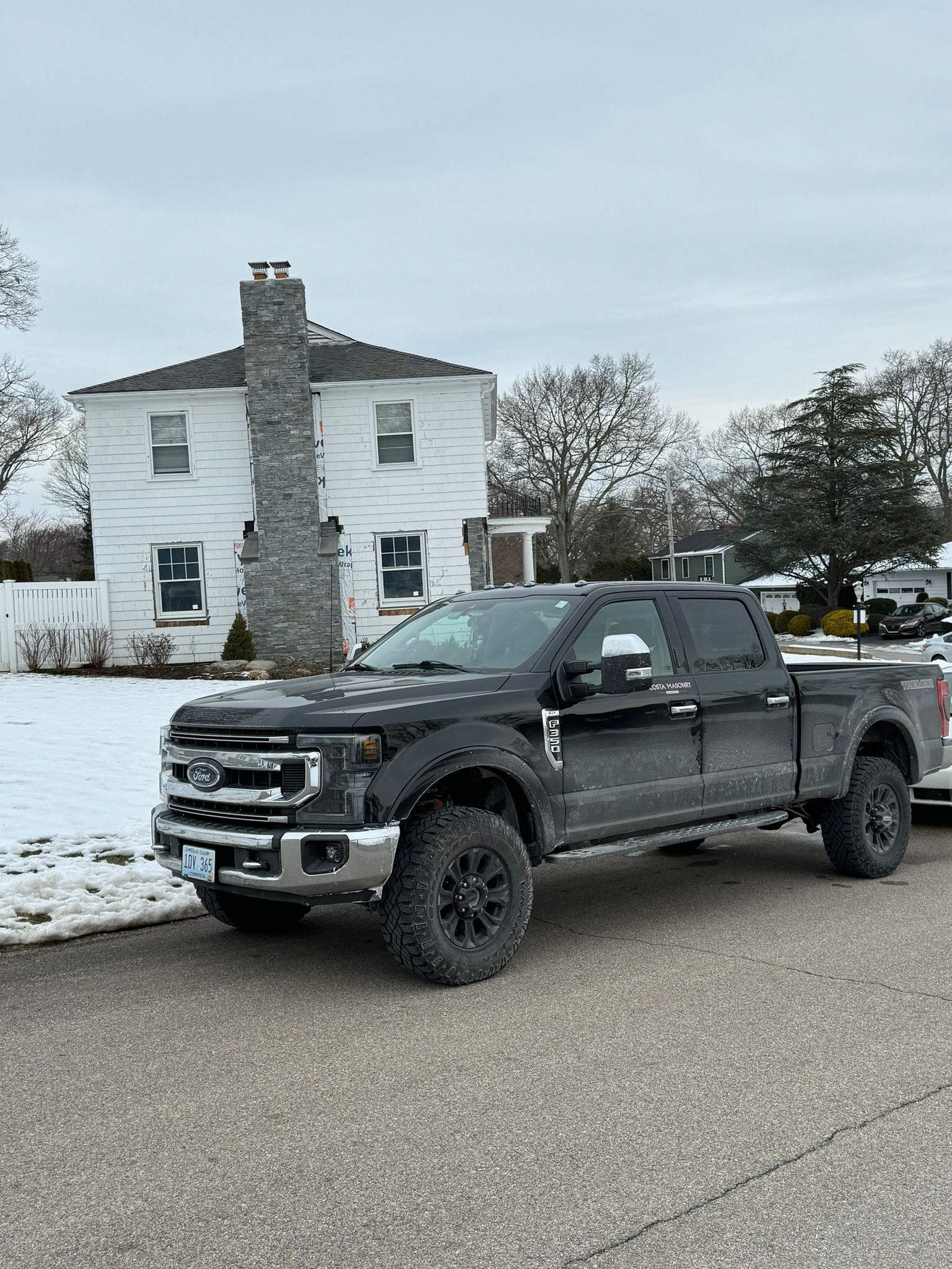 a black truck is parked on the side of the road in front of a white house