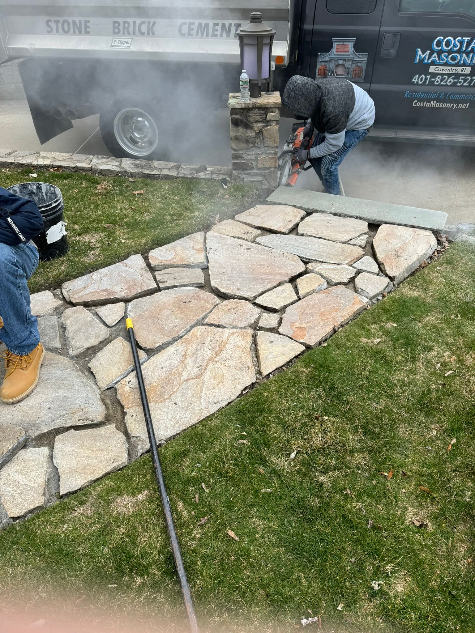 A man is cutting a stone walkway with a chainsaw