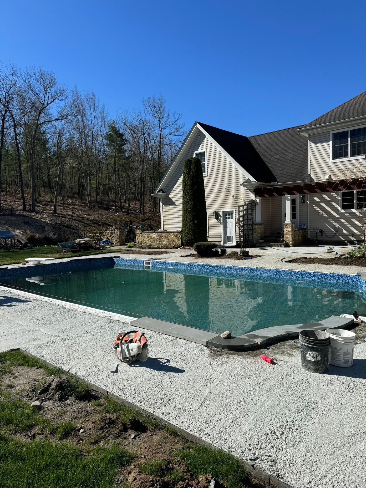 A large swimming pool is being built in front of a house