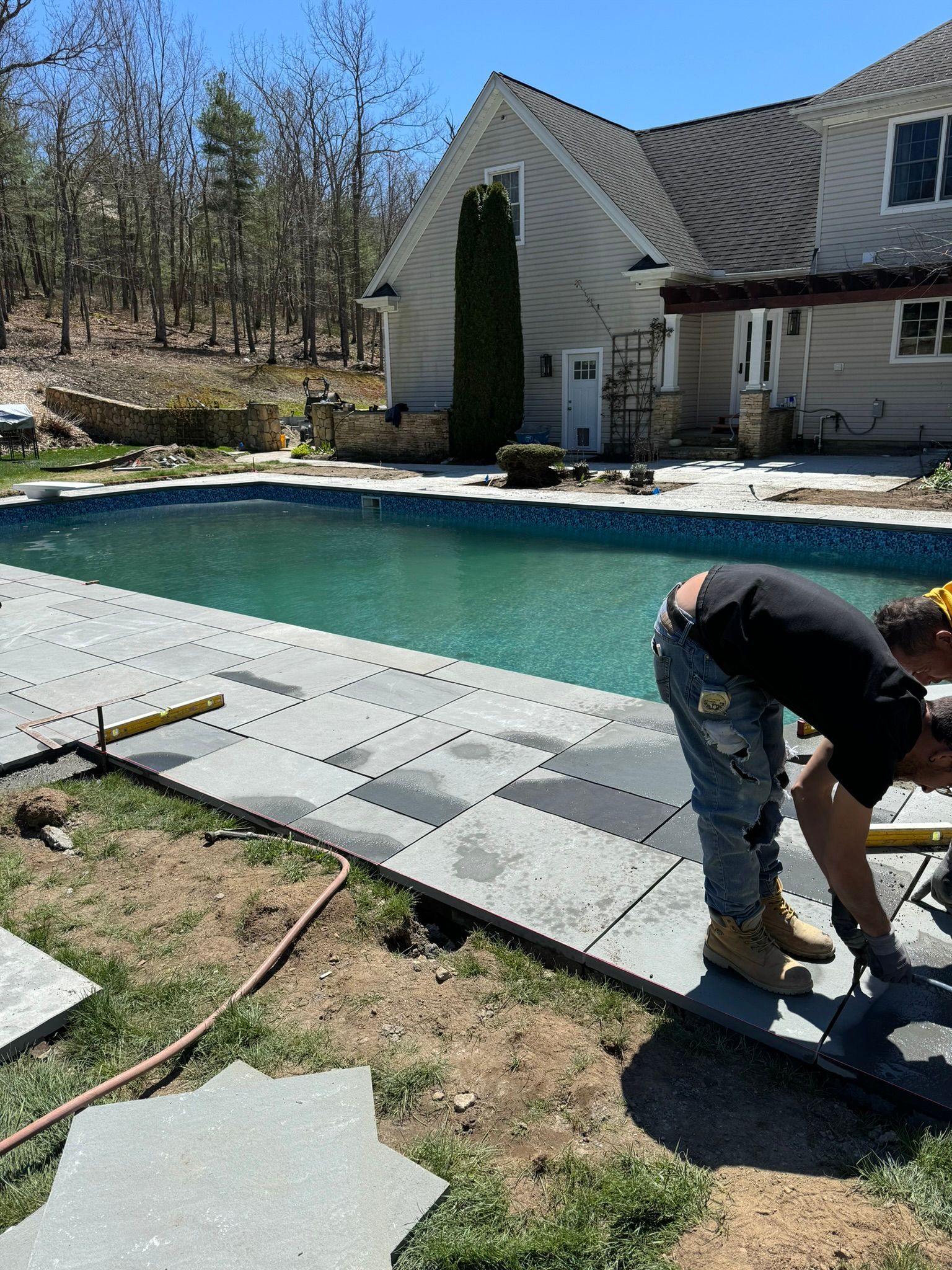 A man is working on a patio next to a swimming pool