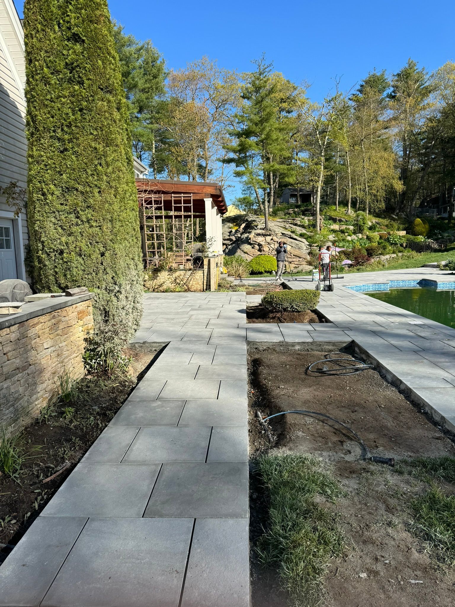 A concrete walkway leading to a swimming pool in a backyard