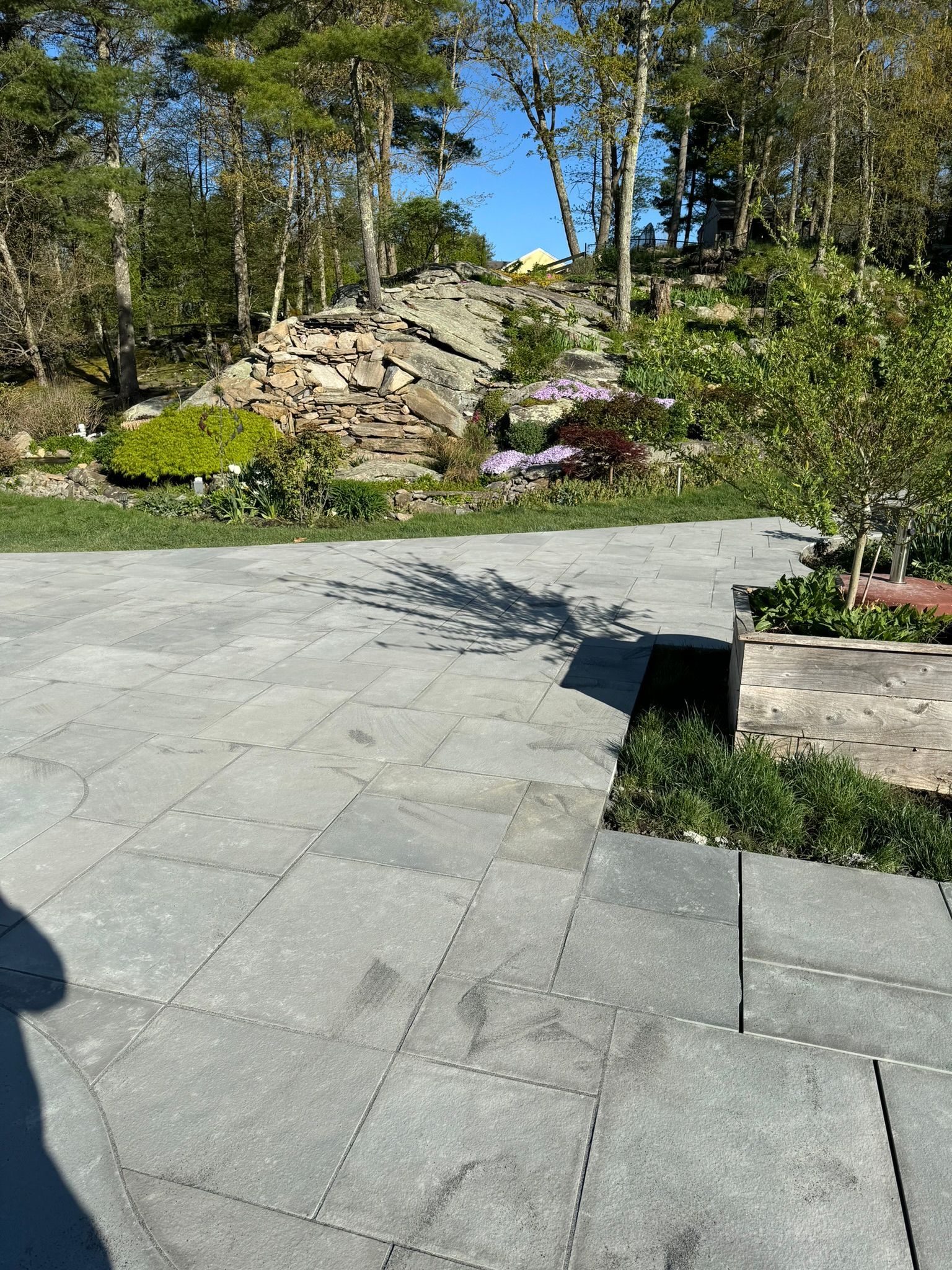 A patio with a rock in the background and trees in the background