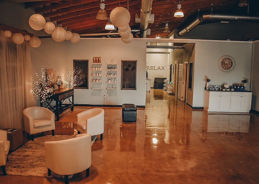 Spacious waiting area with white armchairs, paper lanterns, and a polished orange floor.