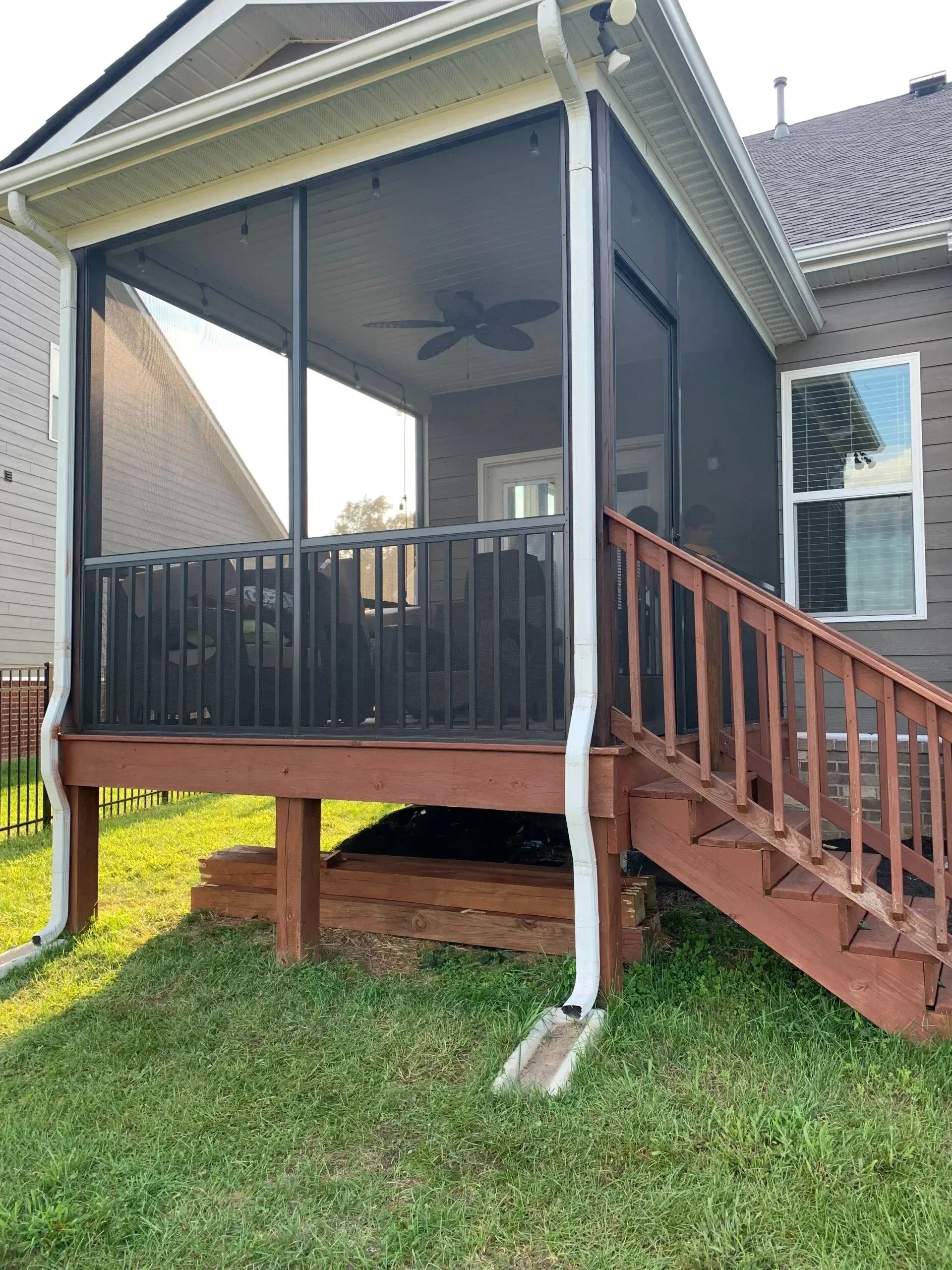 Screened porch with dark screens, brown deck and stairs, white trim, and a ceiling fan.