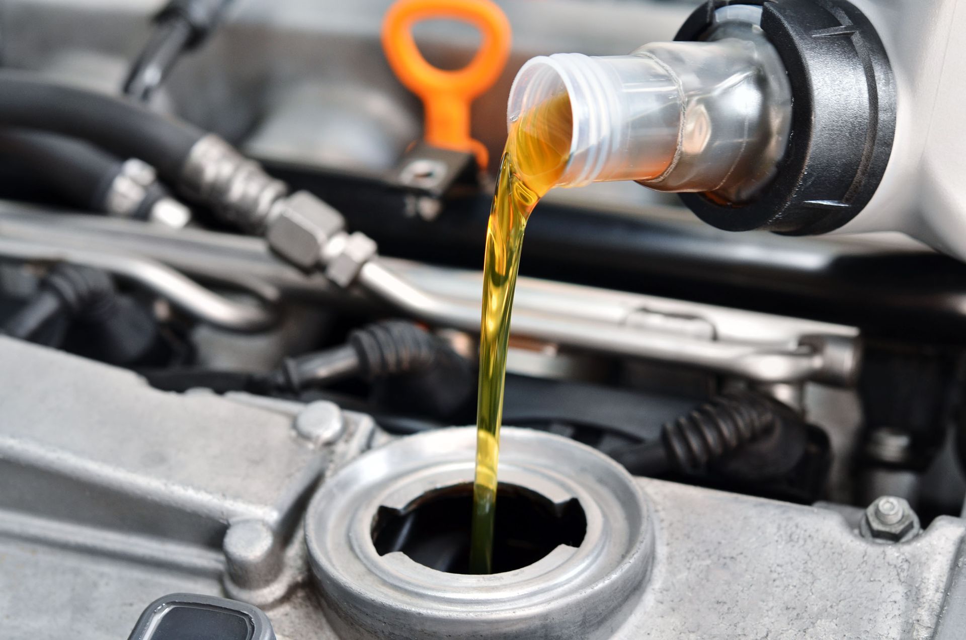 Pouring oil into a car engine; a close-up shows the oil bottle pouring oil into the engine's oil filler opening.